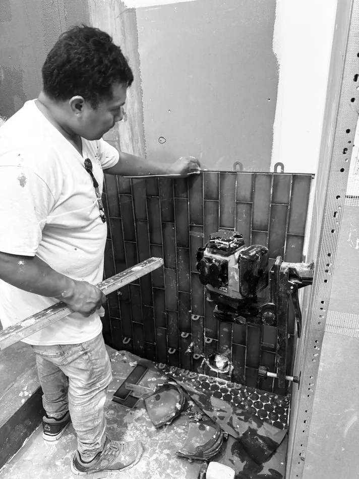 Mason setting vertical ceramic tile during a bathroom renovation