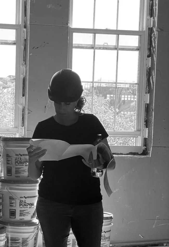 Architect in a hard hat reviewing drawings at a renovation site